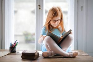 Young Girl Sitting on the table reading