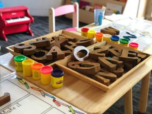 play letters in square containers and play-doh on a table. 